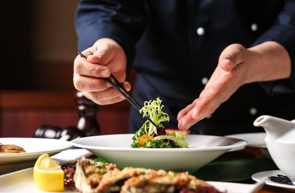 A chef finishing a dish at the pass